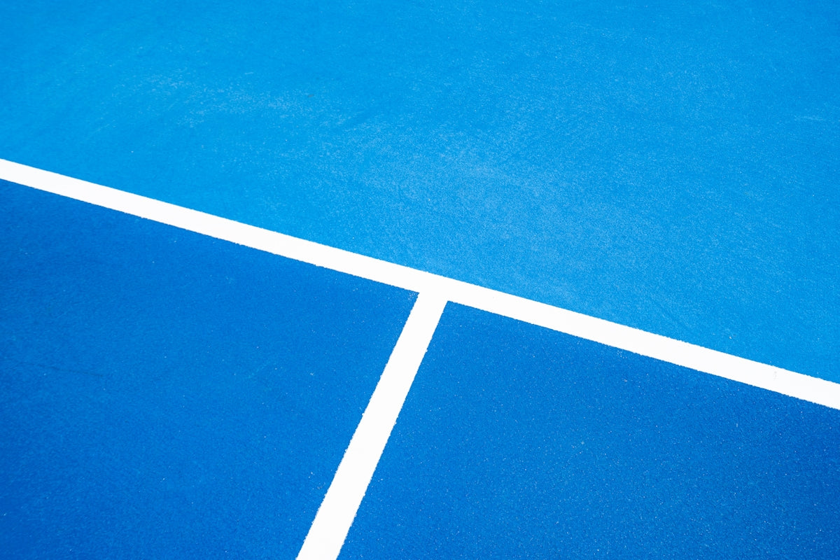A blue tennis court with white lines on it